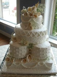All OURS Catering, Charlotte — A gorgeous detailed 4 layer Wedding Cake. Seven layers come together to make this customized cake. Several designs can be incorporated to produce the ideal cake for each Brides Dream Cake. The flowers on this cake are all hand sculpted from rich white chocolate clay. Detail is the key, the corneli lace continues to the cake board to create continuity in the design. View our website for more impressive cakes.