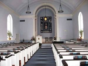 Sanctuary, First Unitarian Universalist Society of Albany, Albany — Our sanctuary is known for its excellent acoustics and has a Steinway piano and a Carlson organ. Built in 1925 in Colonial style, the sanctuary has a barrel vault ceiling and tall arched windows. The room is light and airy in the day and glows softly at night. Up to 196 can be seated in the cushioned pews, plus another 14 in the choir pews at the front right. It has a sound system. Food and beverages are not permitted in this space.