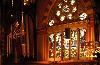 Sanctuary, Old South Church, Boston — Look straight ahead (east) and you will see, hung above the chancel area, the delicate Great Cross, designed by John McConnell and installed in 1990. At the east wall, a five-paneled stained glass window depicts the Announcement of the Birth of Christ to the Shepherds. Above it is the Christmas Manger Scene surrounded by seven angels playing musical instruments. To the left and right are the + Alpha and Omega Windows depicting the first and last letters of the Greek alphabet. These symbolize that God is the first and last, the beginning and the end (Revelation 22:13). The birth of Christ and the risen Christ, represented by the empty cross, are the central theological themes of this Congregational Sanctuary.