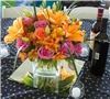 Sparks Florist, Sparks — A warm and elegant centerpiece of orange asiatic lilies, orange and hot pink premium Eufloria roses, orange alstroemeria, white lisianthus, and lily grass.