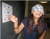 Education by Entertainment, Daytona Beach — Esther Cameron having a great time pasting a sticker on a chart.  Esther is blindfolded and is receiving directions from another student who is wearing a set of goggles which make everything appear to be upside down.