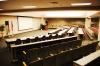 The Atrium At National Composite Center, Dayton — A front view of the auditorium which has a large screen and projector set up. As well as sound equipment with podium.